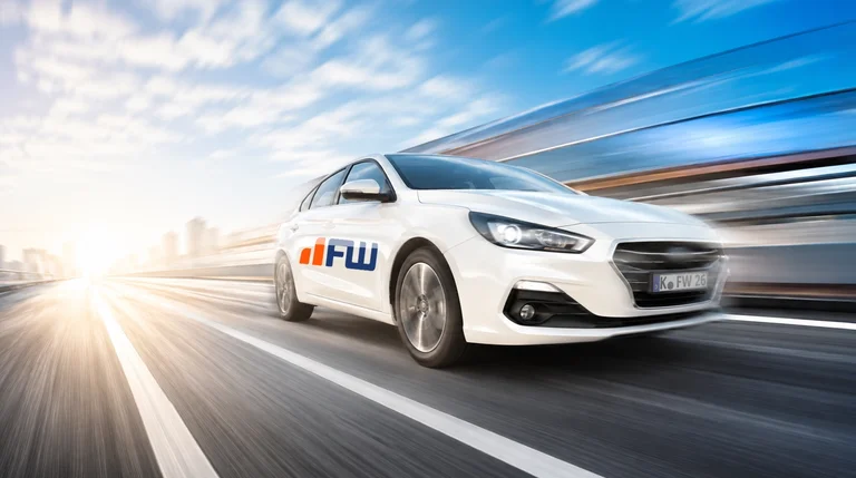 Weißer FahrerWerk Fahrschulwagen in schneller Fahrt auf der Autobahn